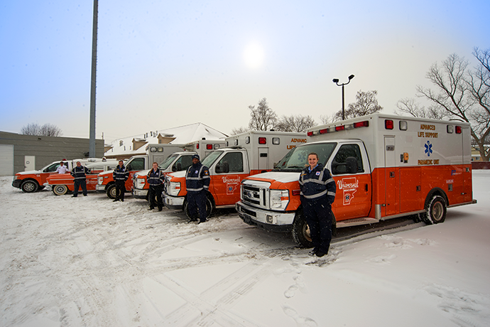 First responders standing lined up next to their ambulances in the snow