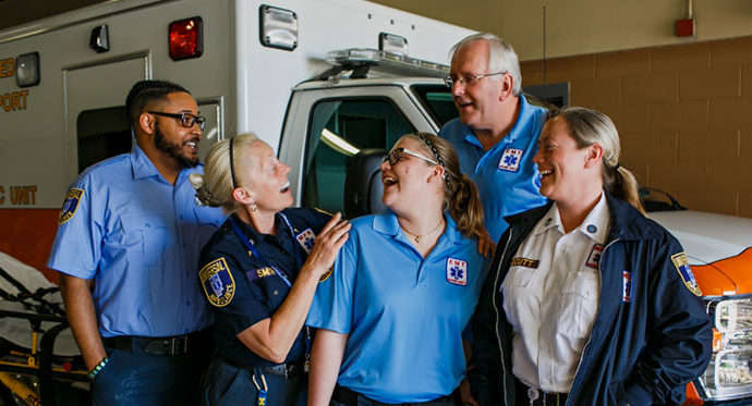 First responders in front of an ambulance talking and laughing together